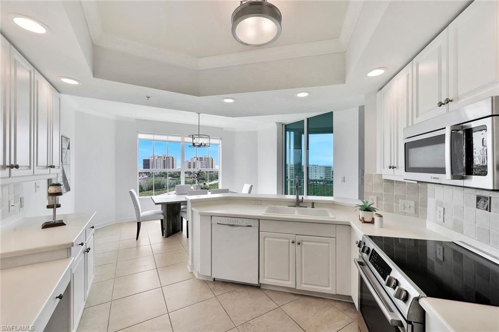 300 Dunes Boulevard, Unit 605 Naples, FL 34110 - Photo 9 of 37 a kitchen with stainless steel appliances kitchen island granite countertop a sink and cabinets