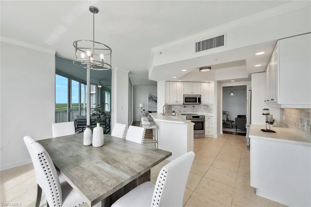 300 Dunes Boulevard, Unit 605 Naples, FL 34110 - Photo 10 of 37 a dining room with wooden floor a chandelier a wooden table and chairs