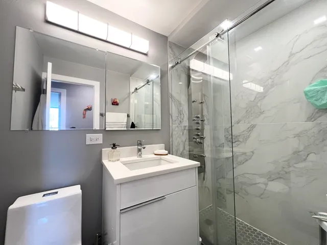 a bathroom with a sink mirror and a toilet