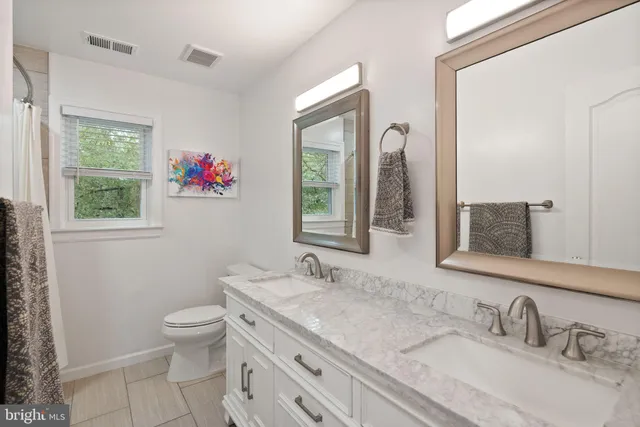 a bathroom with a granite countertop sink mirror and a toilet