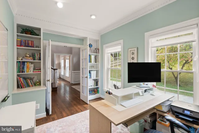 a view of a workspace with furniture and a large window