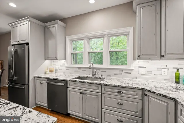 a kitchen with granite countertop a sink stainless steel appliances and cabinets