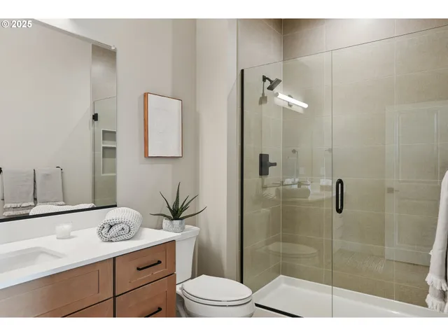 a bathroom with a granite countertop sink a toilet a mirror and shower