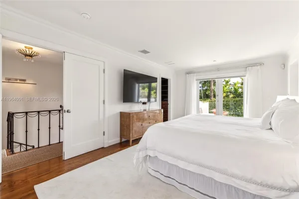 a bedroom with a large bed a flat tv screen and large window