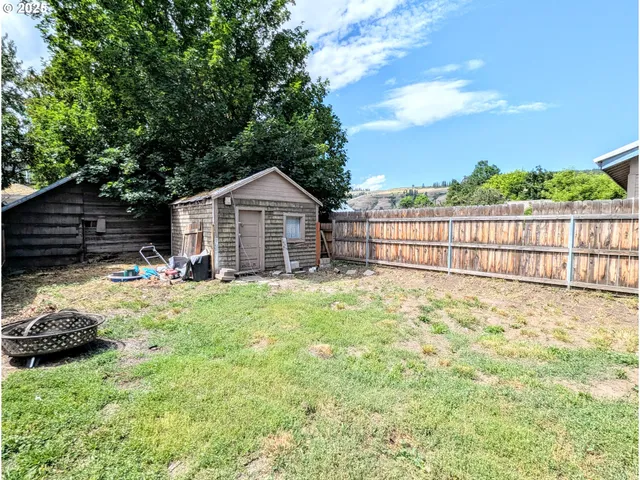 a view of backyard with table and chairs and wooden fence