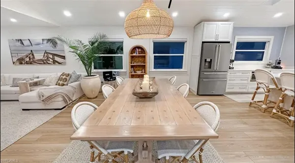 a kitchen with stainless steel appliances kitchen island granite countertop a stove a refrigerator a oven a sink a dining table and chairs with wooden floor