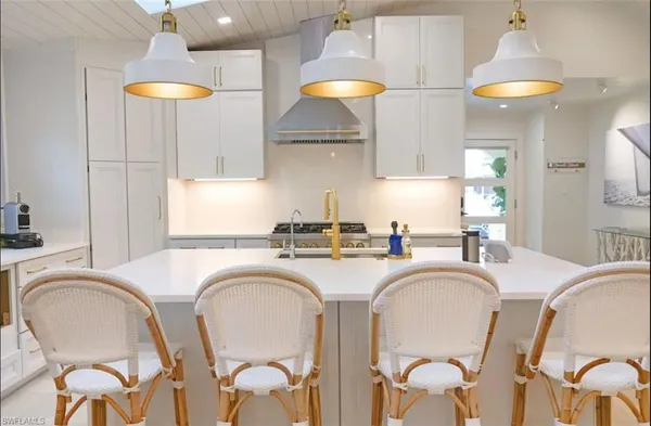 a kitchen with stainless steel appliances granite countertop a dining table chairs sink and cabinets
