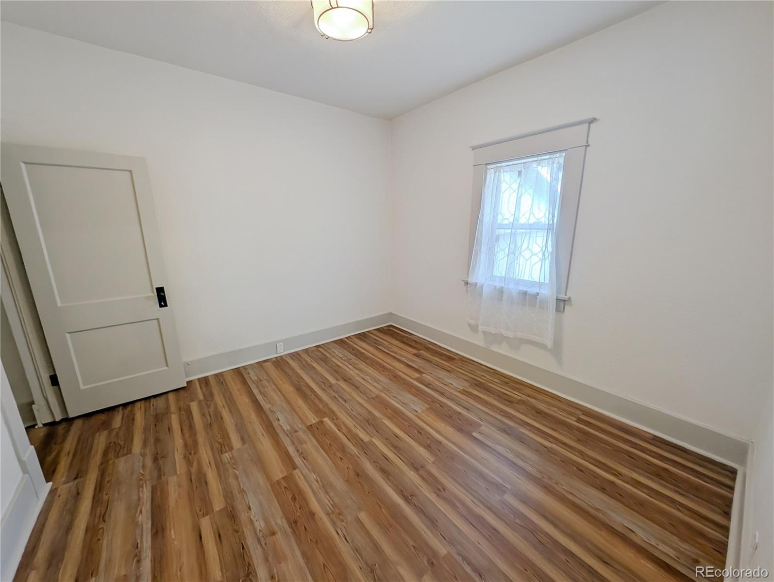 710 Carson Street Brush, CO 80723 - Photo 16 of 30 an empty room with wooden floor and windows