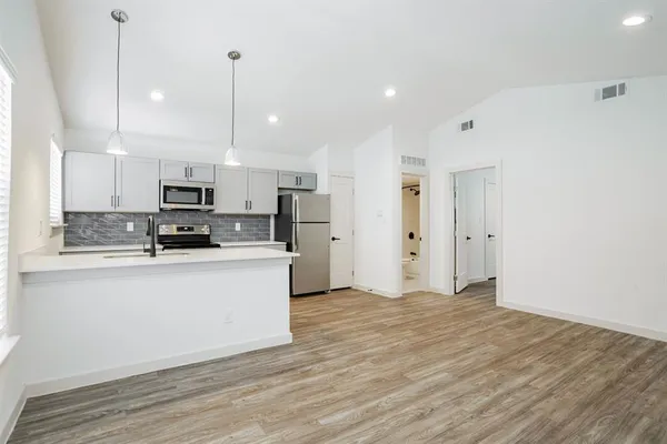 a large white kitchen with stainless steel appliances granite countertop a stove a sink and white cabinets