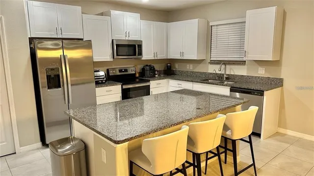 a kitchen with stainless steel appliances granite countertop a sink refrigerator and microwave