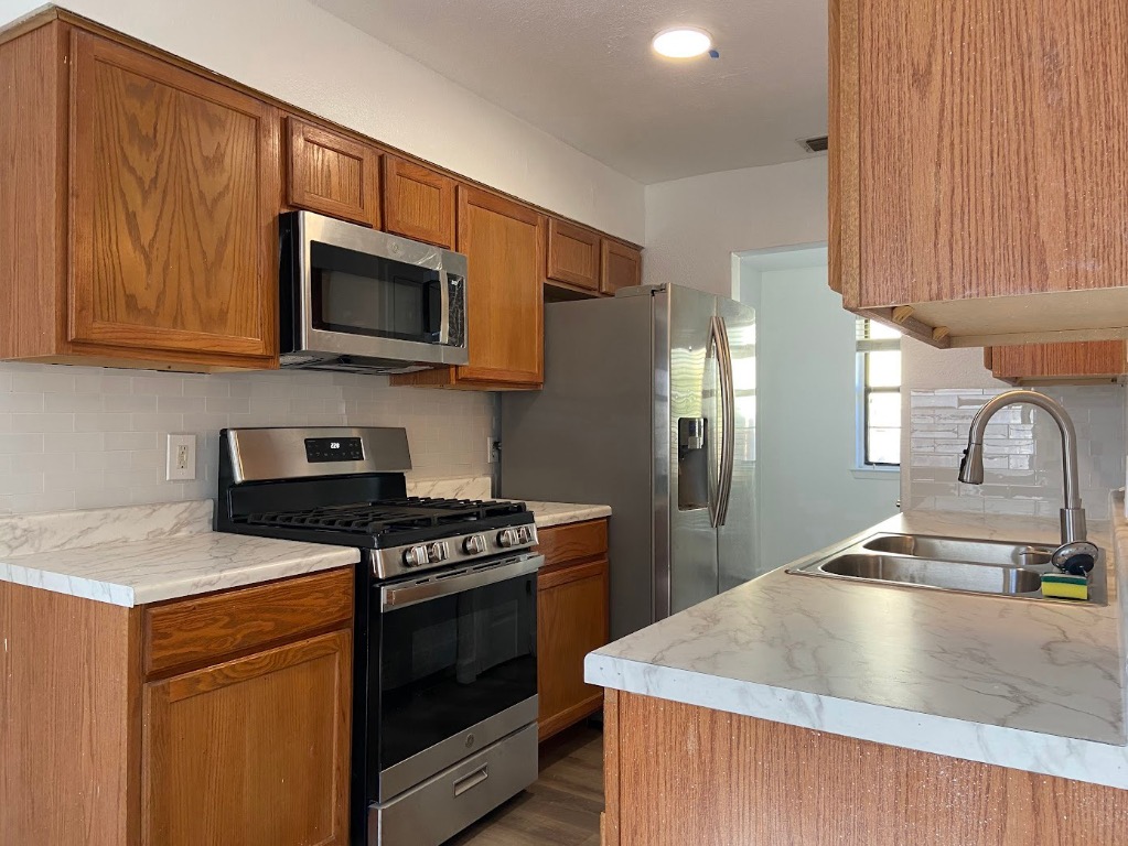 a kitchen with stainless steel appliances granite countertop a stove a sink and a microwave