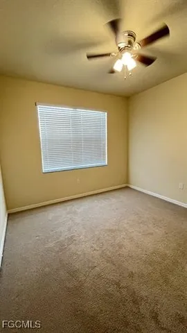 an empty room with a chandelier fan and windows
