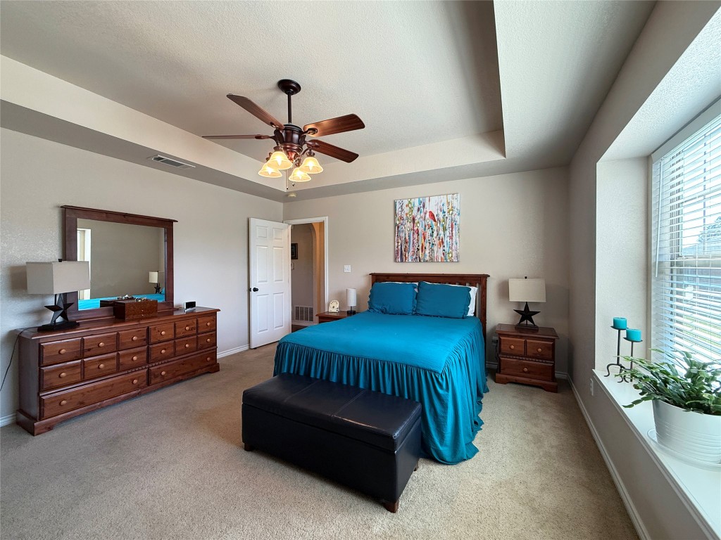 1502 Hamilton Street Burnet, TX 78611 - Photo 13 of 26 a spacious bedroom with a bed and a chandelier