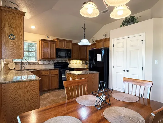 a kitchen with stainless steel appliances granite countertop a stove a sink a dining table and chairs