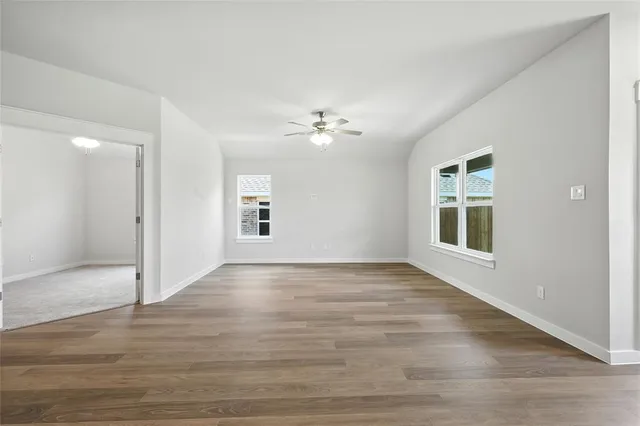a view of an empty room with kitchen and a window