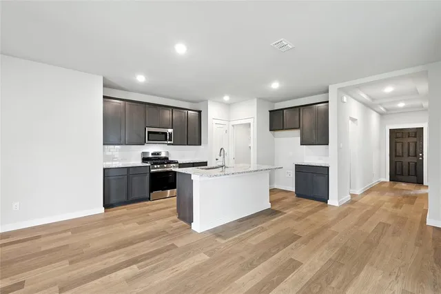 a large kitchen with a stove top oven a sink dishwasher a refrigerator and a oven with wooden floor