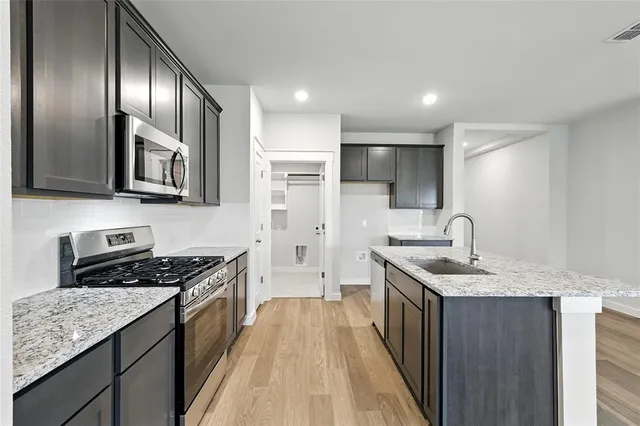 a kitchen with stainless steel appliances granite countertop a sink stove and refrigerator