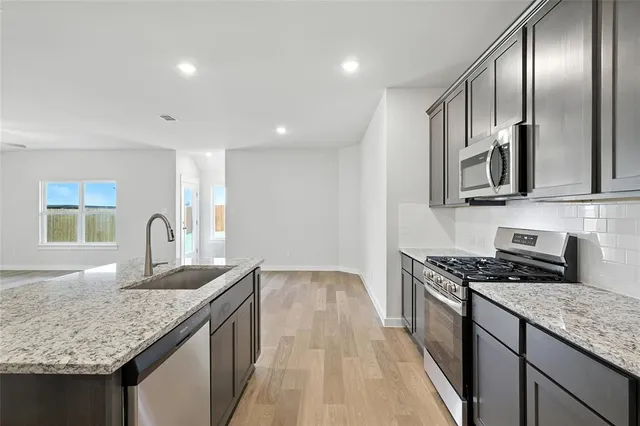 a kitchen with stainless steel appliances granite countertop a sink stove and refrigerator