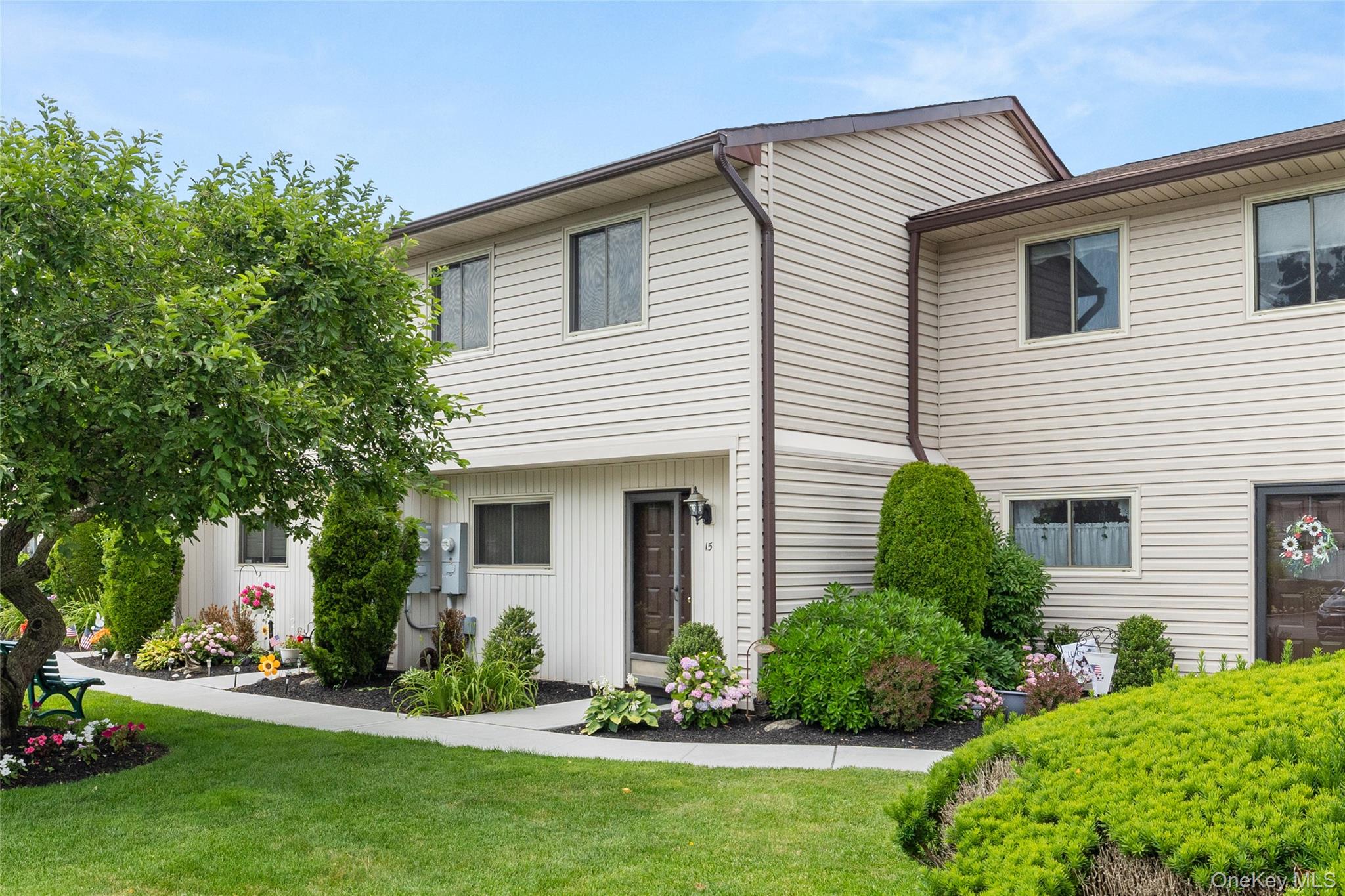 650 Newbridge Road, Unit 15 East Meadow, NY 11554 - Photo 2 of 20 a front view of a house with a garden and plants