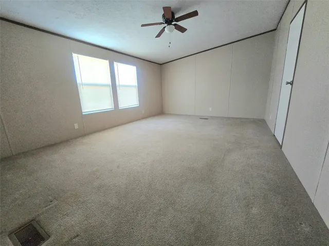an empty room with windows and ceiling fan