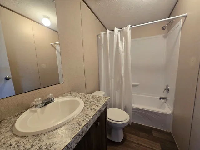 a bathroom with a granite countertop sink toilet and shower