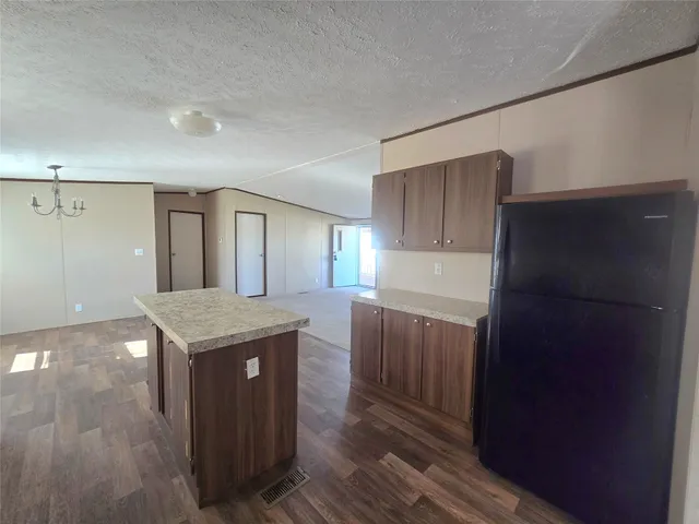 a kitchen with kitchen island granite countertop wooden cabinets and refrigerator