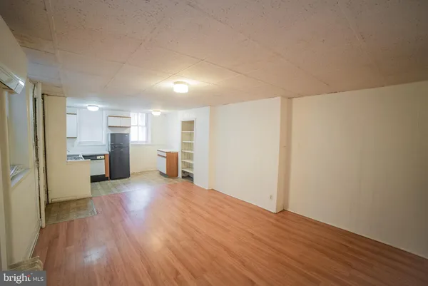 a view of a big room with wooden floor and a kitchen