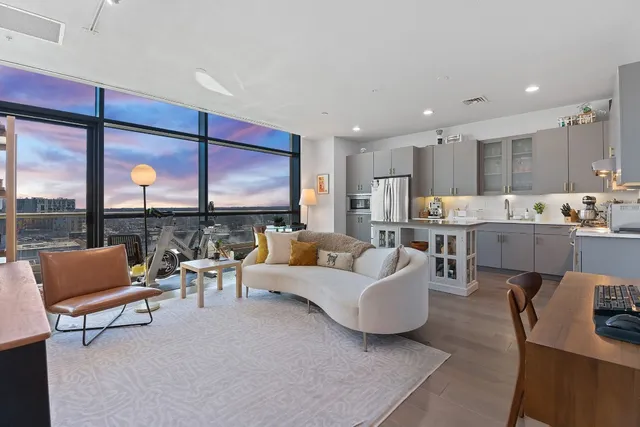 a living room with furniture kitchen view and a large window