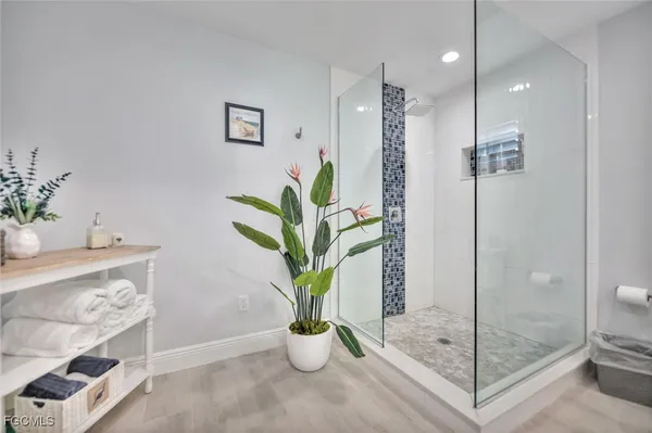 a bath room with a glass door shower and a plant