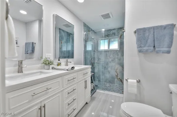 a spacious bathroom with a granite countertop sink toilet a large mirror a vanity and shower