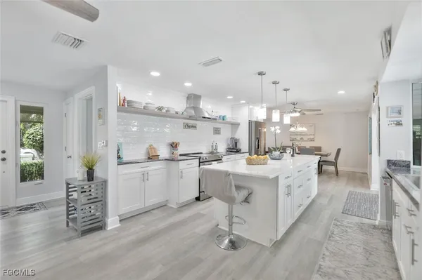 a large white kitchen with lots of counter space wooden floor and appliances