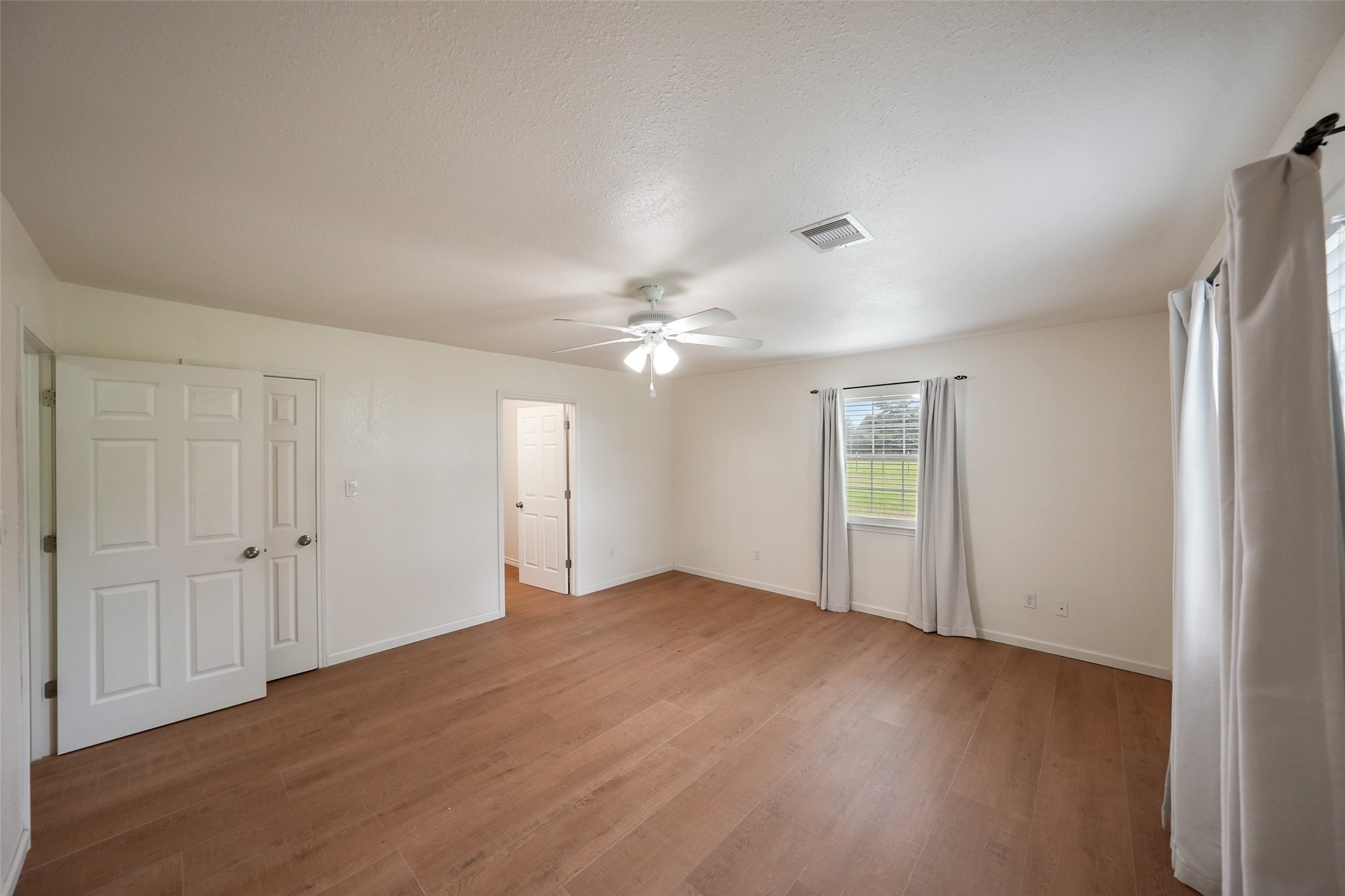 19635 Kermier Road Waller, TX 77484 - Photo 18 of 27 Generous primary suite with dual closets, ceiling fan, and abundant natural light.