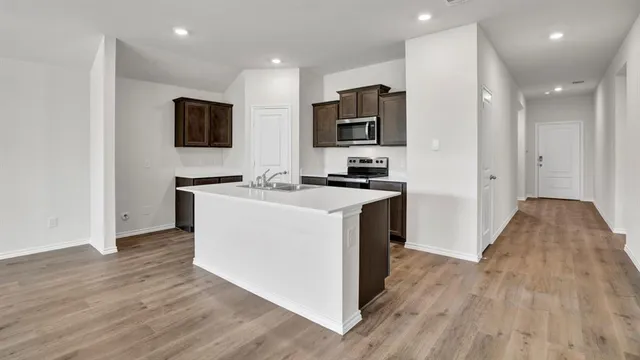 a white kitchen with wooden floor and stainless steel appliances