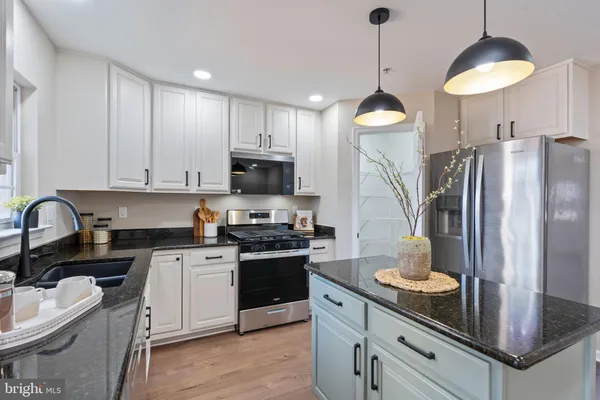 a kitchen with stainless steel appliances granite countertop a sink a stove a refrigerator cabinets and chairs