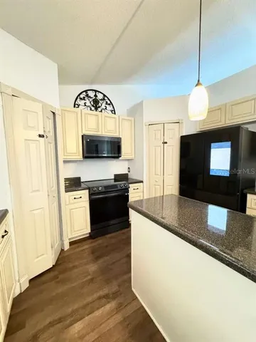 a large kitchen with granite countertop a stove a sink and a wooden floor