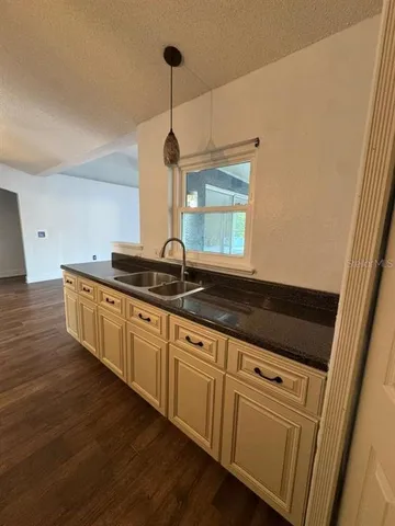 a kitchen with granite countertop white cabinets and a wooden floor