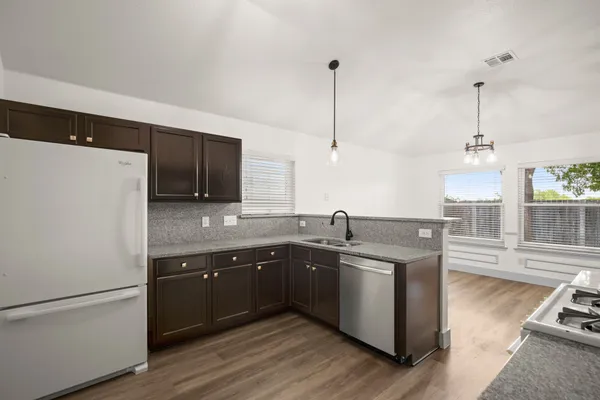 a kitchen with stainless steel appliances granite countertop a sink a stove and a refrigerator
