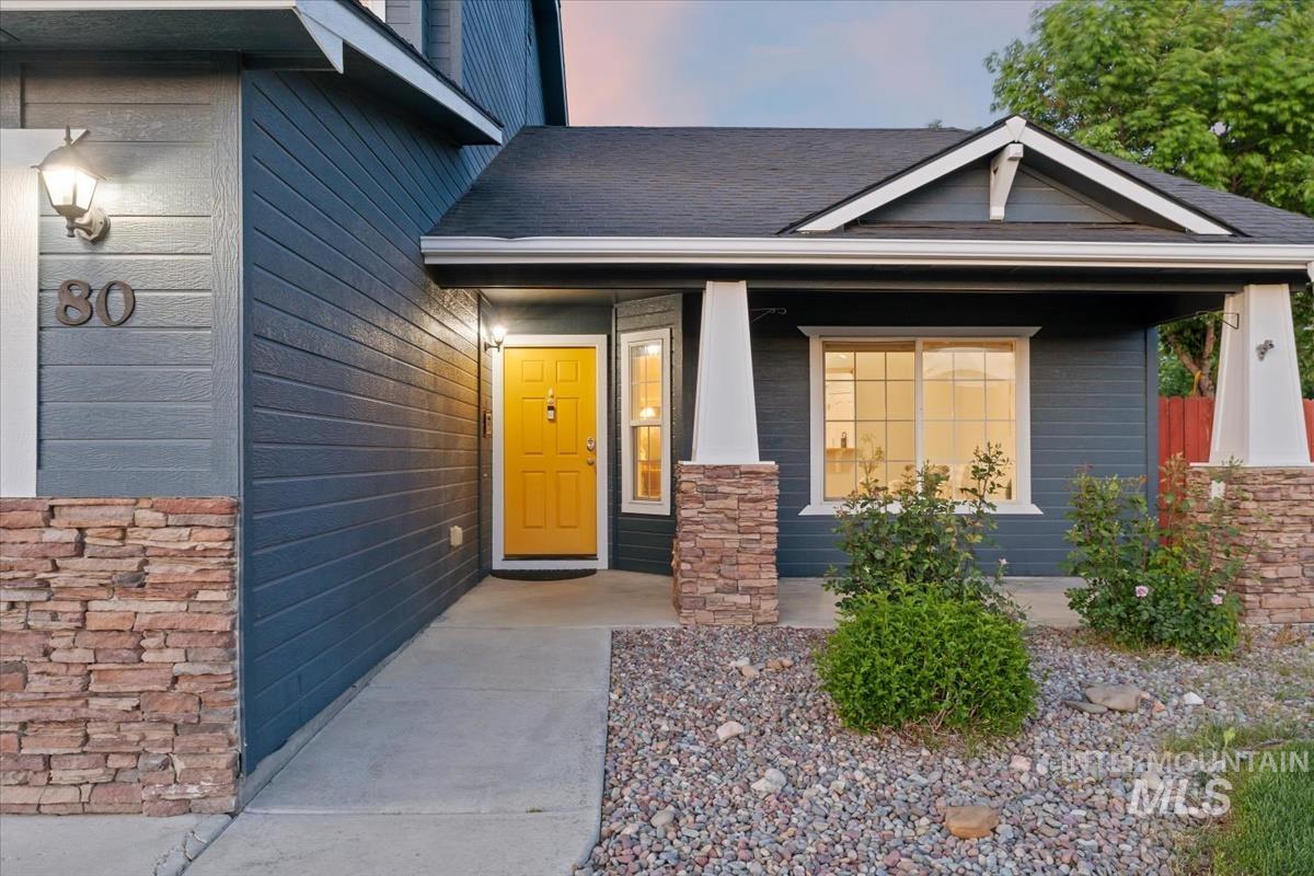 80 Cobblestone Court Middleton, ID 83644 - Photo 2 of 48 Welcoming exterior with deep blue siding, a vibrant yellow entry door, stone veneer accents, white trim, and a covered porch