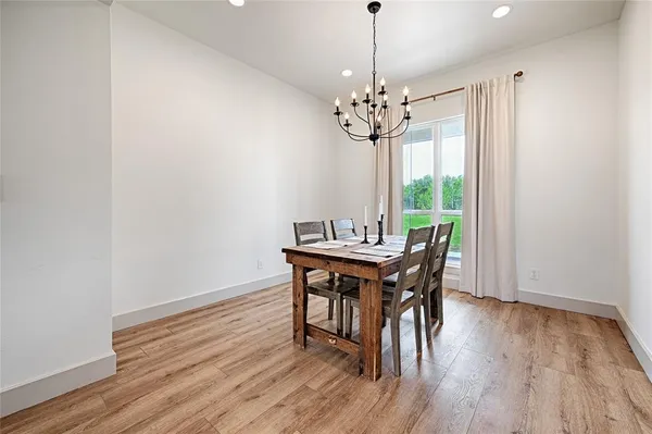 a view of a dining room with wooden floor a chandelier a wooden table and chairs