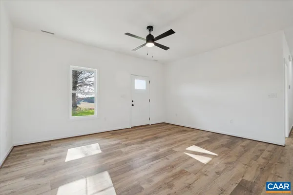 an empty room with a window and ceiling fan