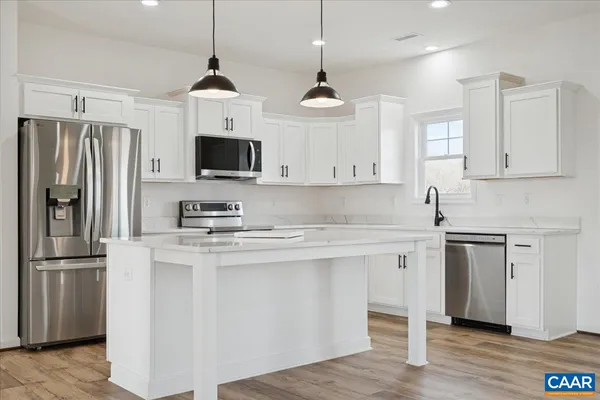 a kitchen with stainless steel appliances granite countertop a refrigerator a sink dishwasher a stove and white cabinets with wooden floor