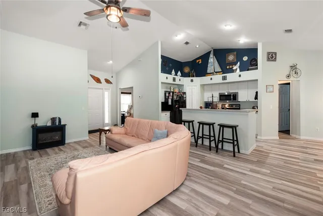 a living room with stainless steel appliances kitchen island granite countertop furniture a rug kitchen view and a chandelier