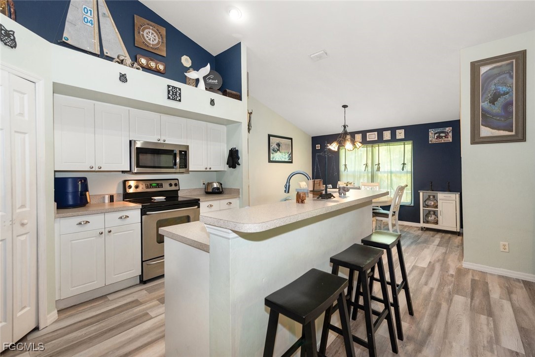 2005 Mc Arthur Avenue Alva, FL 33920 - Photo 8 of 32 a kitchen with stainless steel appliances a stove a sink dishwasher a oven with white cabinets and wooden floor