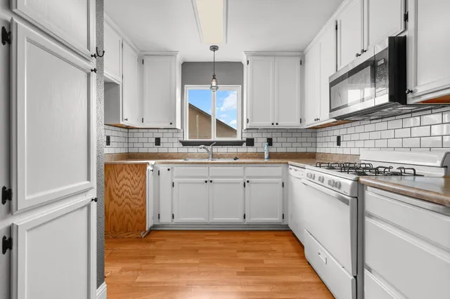 a kitchen with stainless steel appliances granite countertop a stove a sink and a microwave