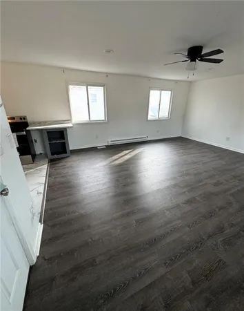 an empty room with windows and ceiling fan