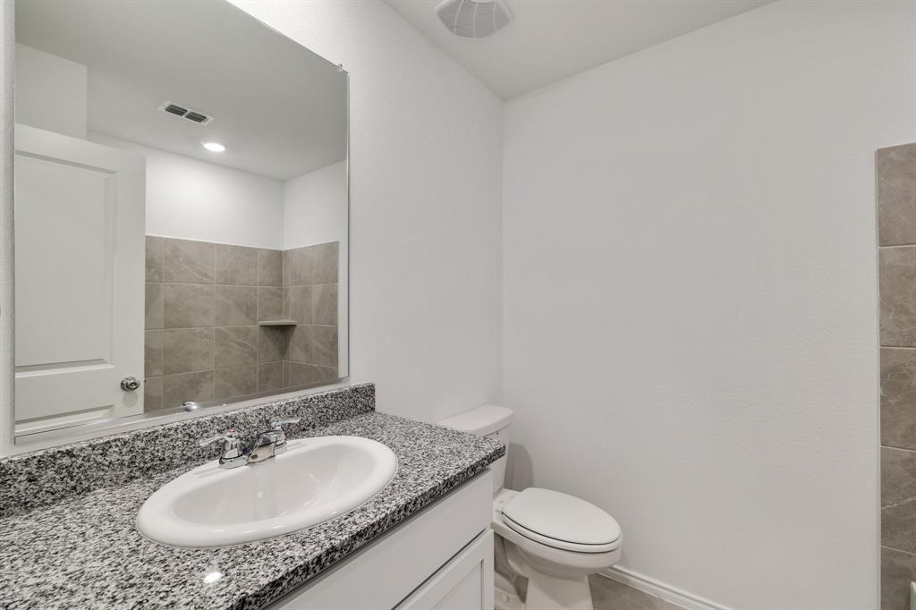 2809 Ozark Circle Little Elm, TX 75068 - Photo 13 of 28 a bathroom with a granite countertop sink a toilet and a mirror
