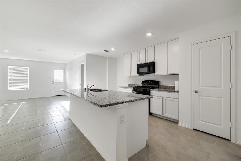 2809 Ozark Circle Little Elm, TX 75068 - Photo 4 of 28 a kitchen with stainless steel appliances granite countertop a sink and a stove top oven with white cabinets
