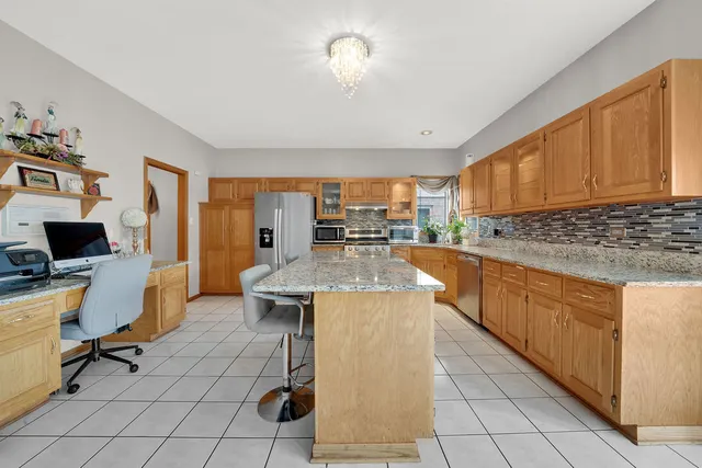 a kitchen with stainless steel appliances granite countertop a stove a sink dishwasher and a refrigerator with wooden cabinets