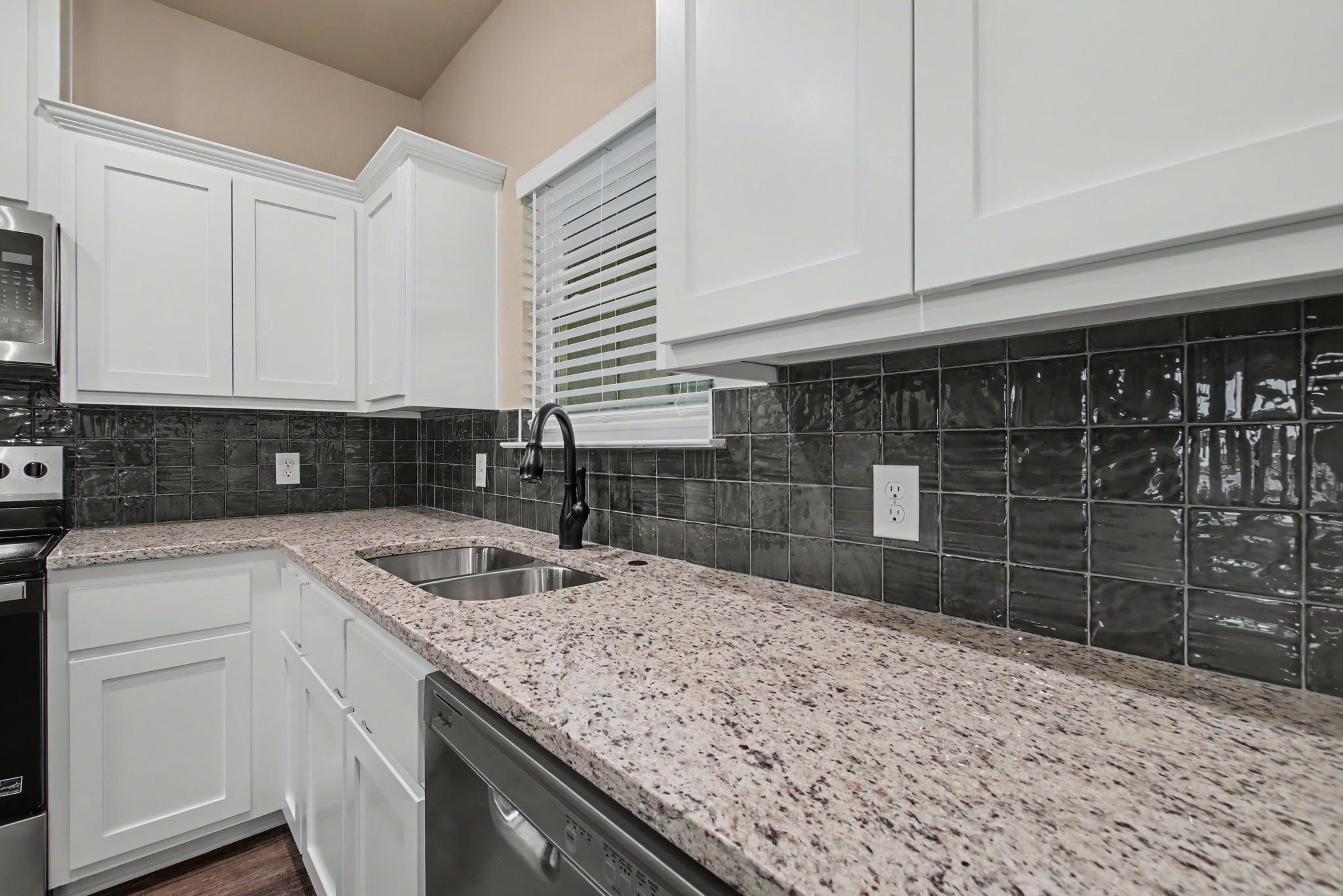 206 Water Wl Road Burnet, TX 78611 - Photo 7 of 25 Gleaming stone countertops pair beautifully with classic shaker cabinets and a modern tiled backsplash.
