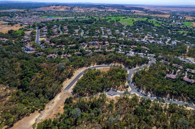 an aerial view of residential house with green space and mountain view in back